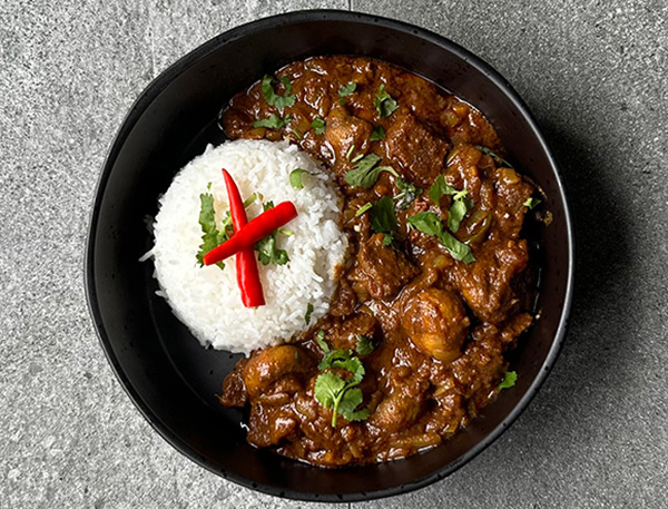 bowl of chicken curry with rice and red chilies garnished with cilantro featuring a six ingredient recipe